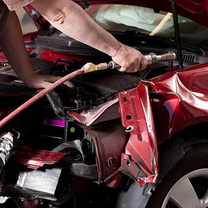 Professional auto repair technician performing collision repair on a vehicle.